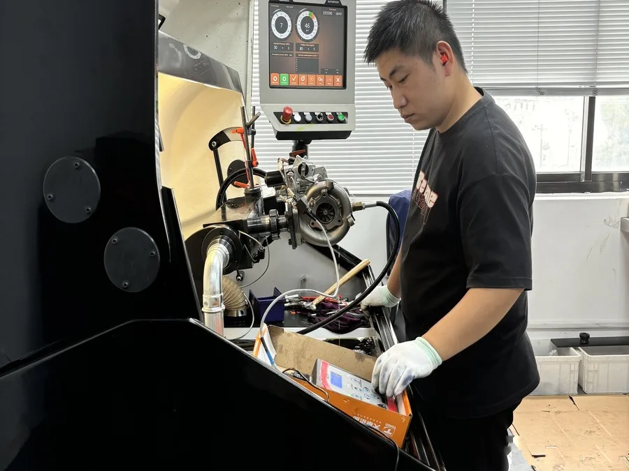 Technician running oil-fed run test and air-leak test on a turbocharger